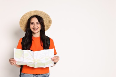 Young tourist in hat with map on white background, space for text