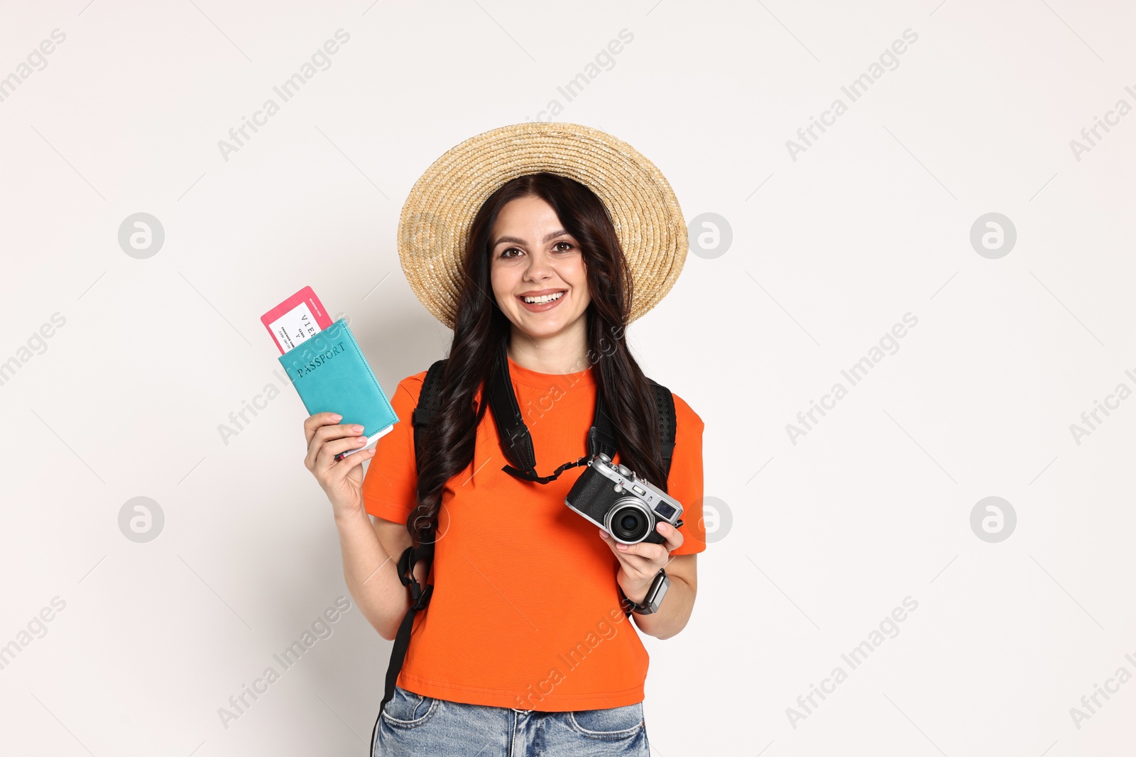 Photo of Young tourist in hat with camera, passport, ticket and backpack on white background