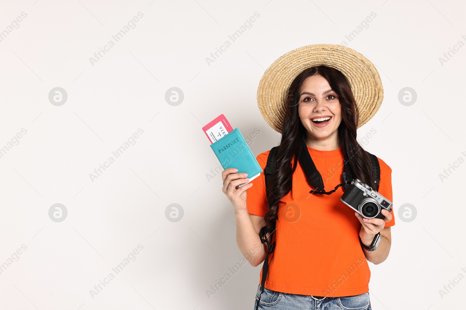 Photo of Young tourist in hat with camera, passport, ticket and backpack on white background, space for text