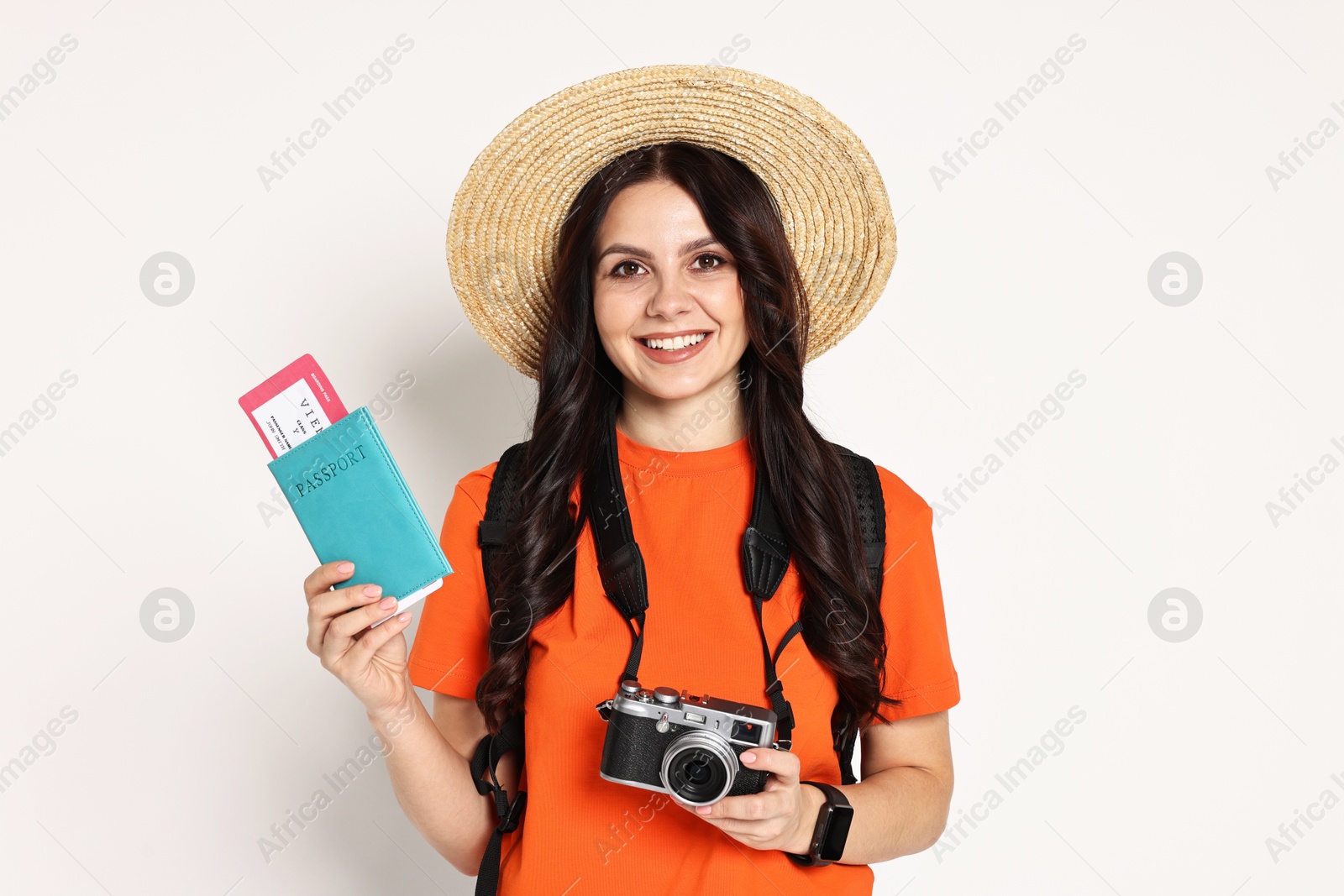 Photo of Young tourist in hat with camera, passport, ticket and backpack on white background