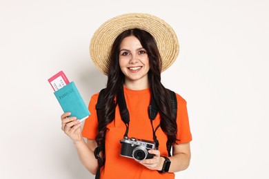 Photo of Young tourist in hat with camera, passport, ticket and backpack on white background