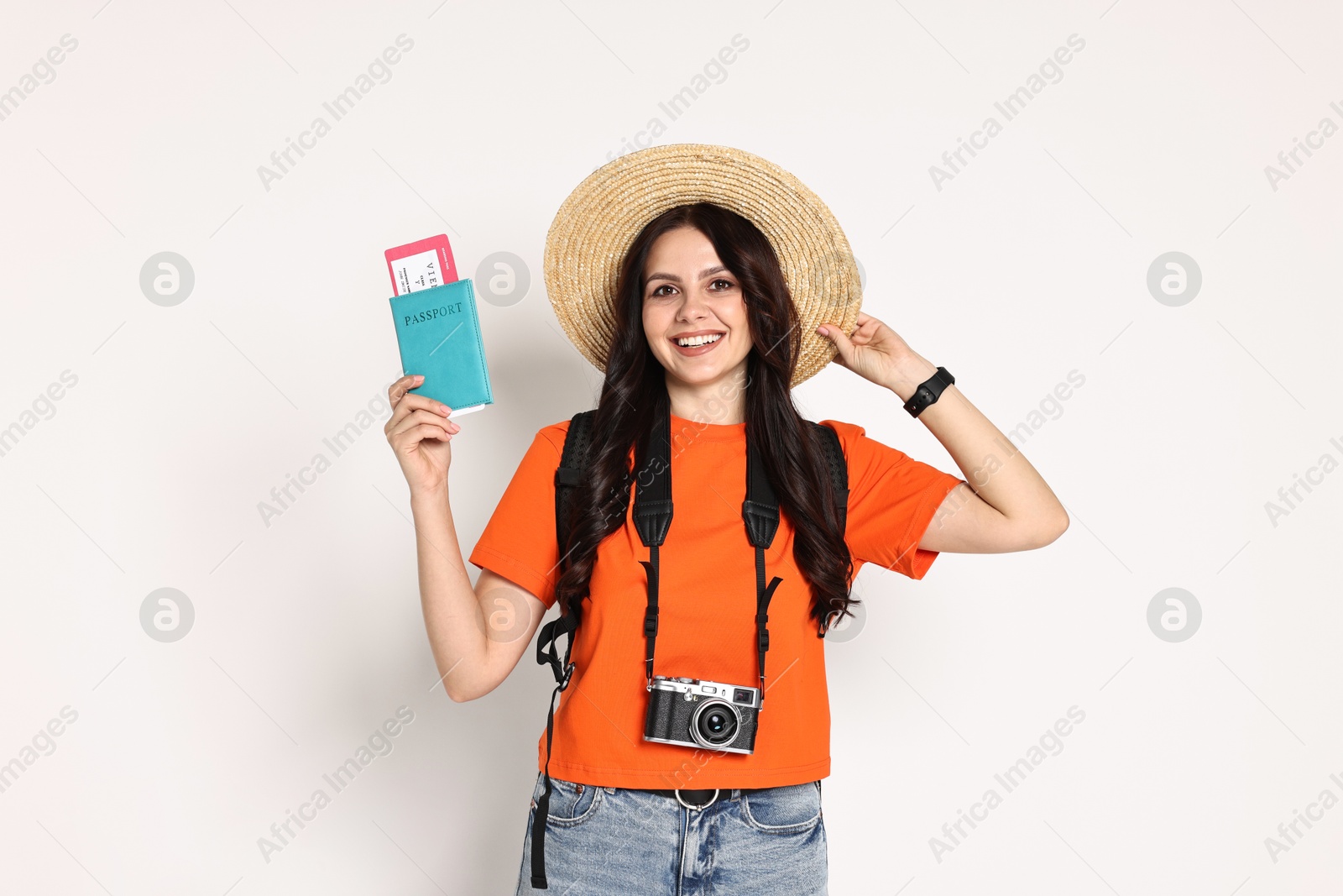 Photo of Young tourist in hat with camera, passport, ticket and backpack on white background