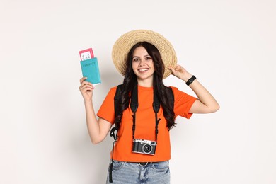 Photo of Young tourist in hat with camera, passport, ticket and backpack on white background