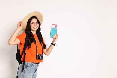 Photo of Young tourist in hat with camera, passport, ticket and backpack on white background, space for text