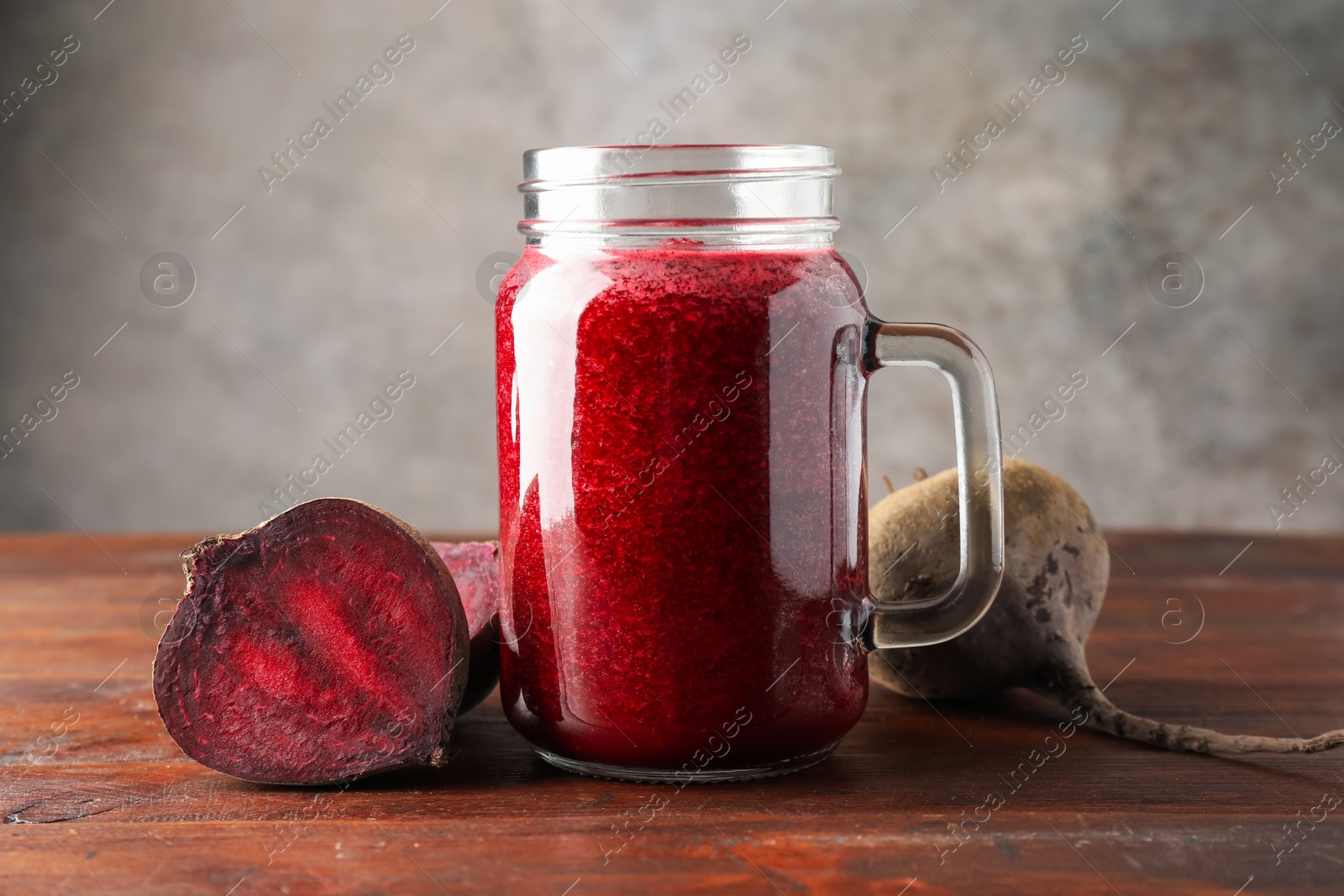 Photo of Fresh beetroot smoothie in mason jar and vegetables on wooden table, closeup