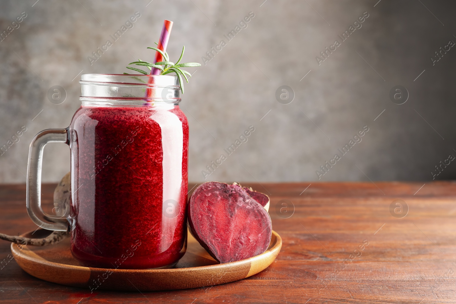 Photo of Fresh beetroot smoothie in mason jar and vegetables on wooden table, closeup. Space for text