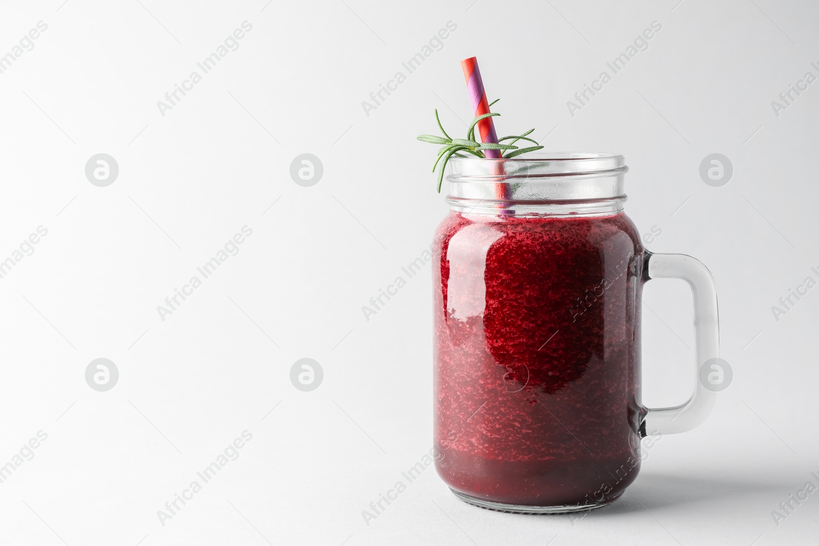 Photo of Fresh beetroot smoothie in mason jar on light background, closeup. Space for text