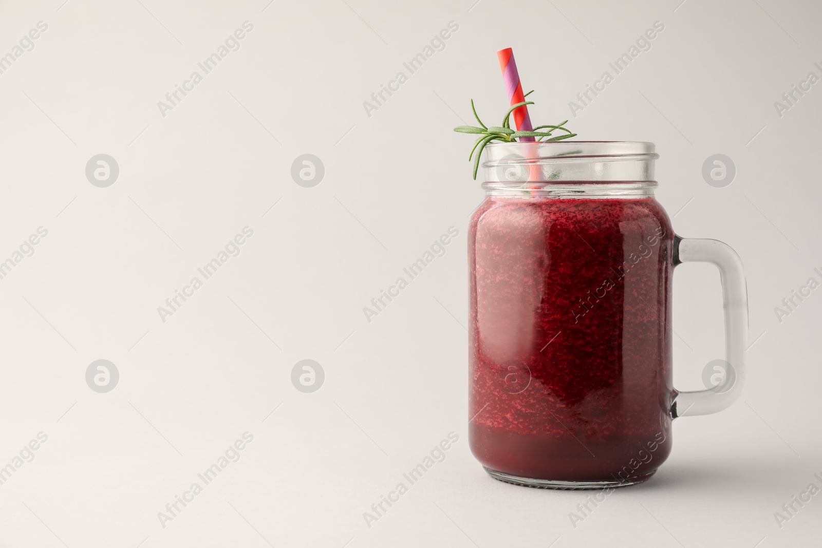 Photo of Fresh beetroot smoothie in mason jar on light grey background. Space for text