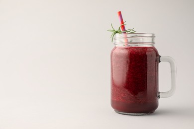 Photo of Fresh beetroot smoothie in mason jar on light grey background. Space for text