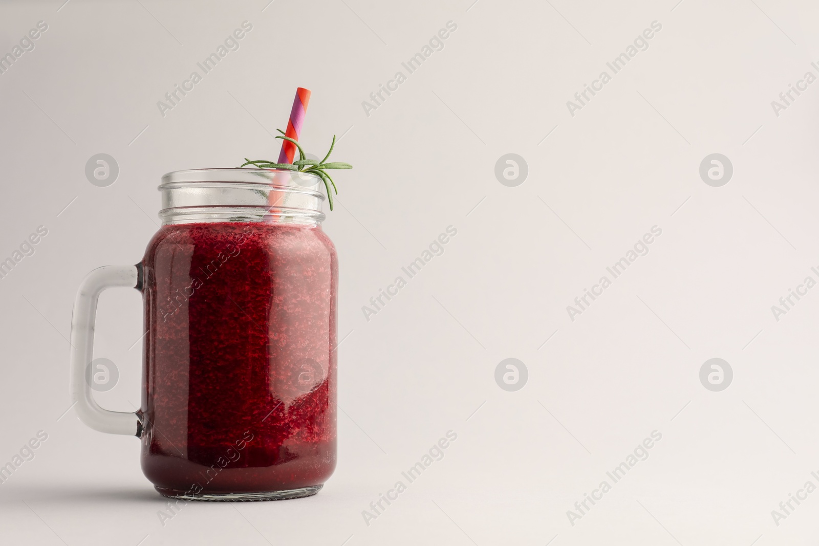 Photo of Fresh beetroot smoothie in mason jar on light grey background. Space for text