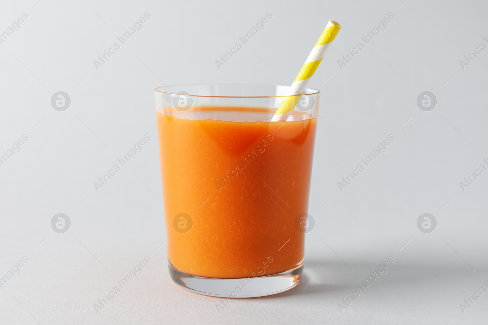 Photo of Fresh carrot smoothie in glass on light grey background, closeup