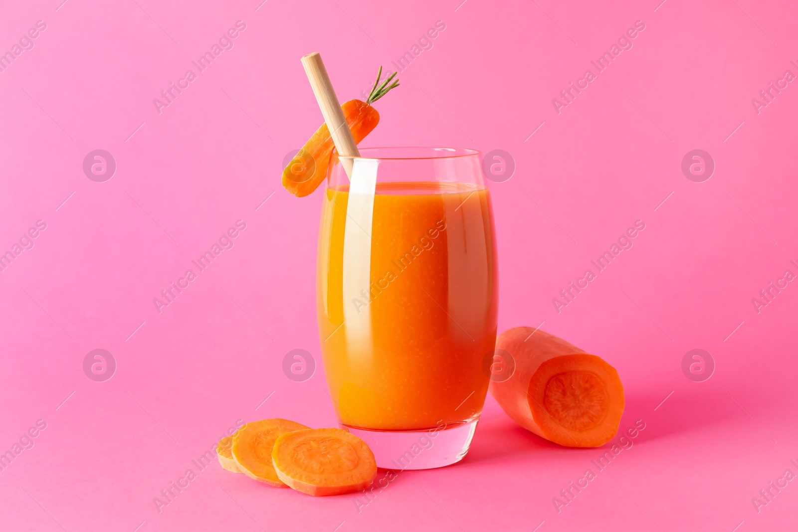 Photo of Fresh carrot smoothie in glass and cut vegetable on pink background, closeup