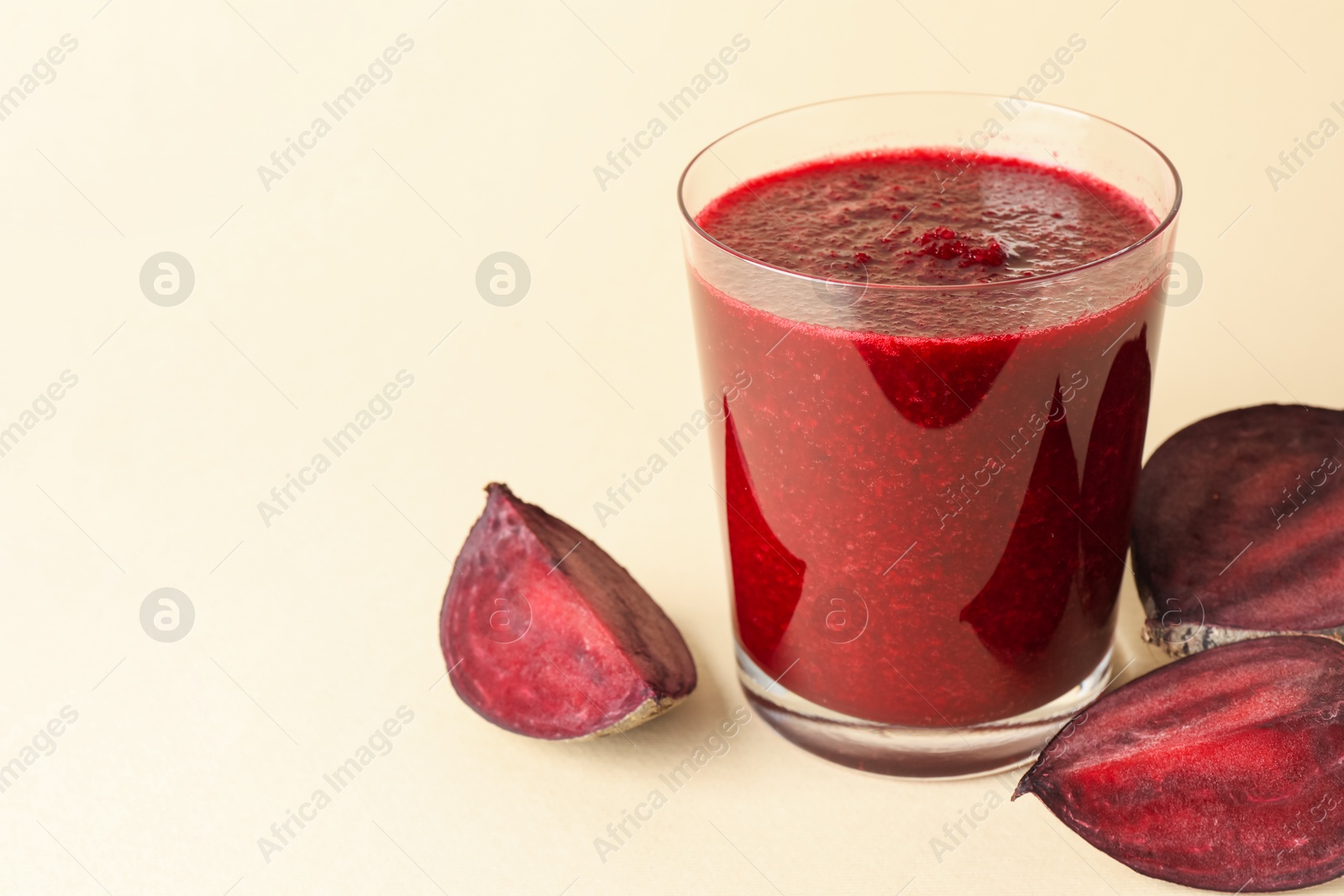 Photo of Fresh beetroot smoothie in glass and cut vegetable on beige background, closeup. Space for text