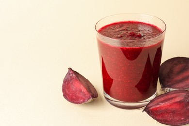 Photo of Fresh beetroot smoothie in glass and cut vegetable on beige background, closeup. Space for text