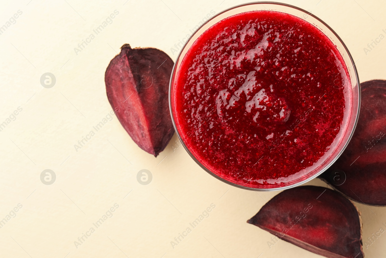 Photo of Fresh beetroot smoothie in glass and cut vegetable on beige background, flat lay. Space for text