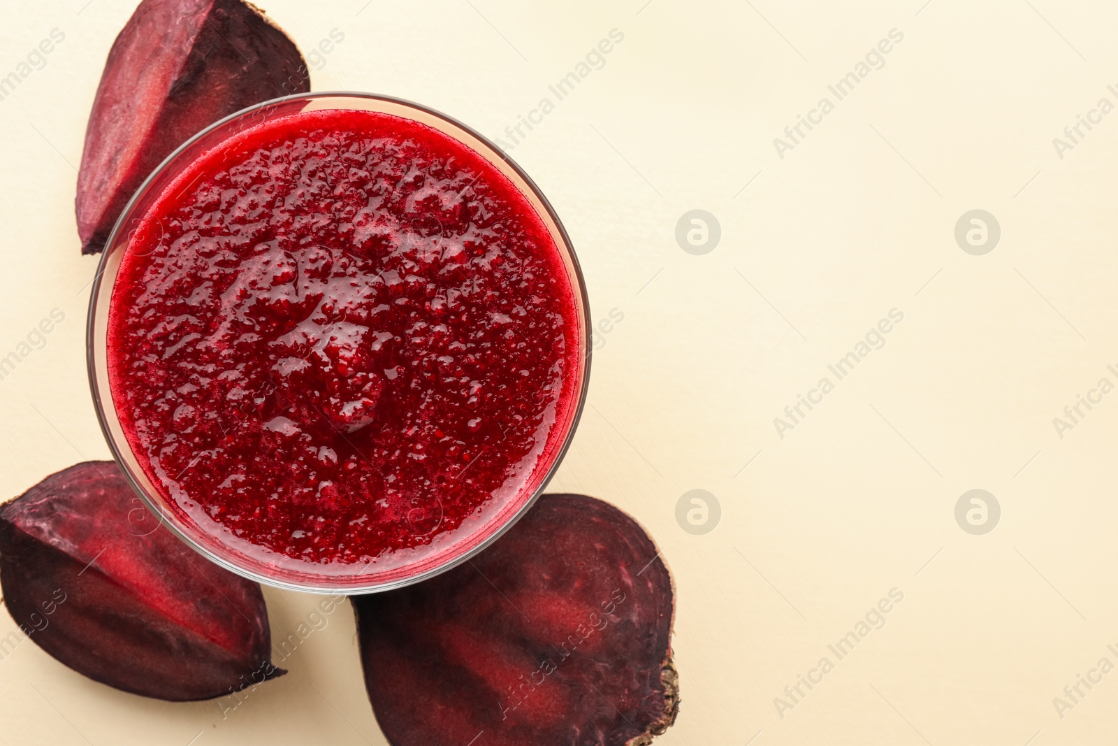 Photo of Fresh beetroot smoothie in glass and cut vegetable on beige background, flat lay. Space for text