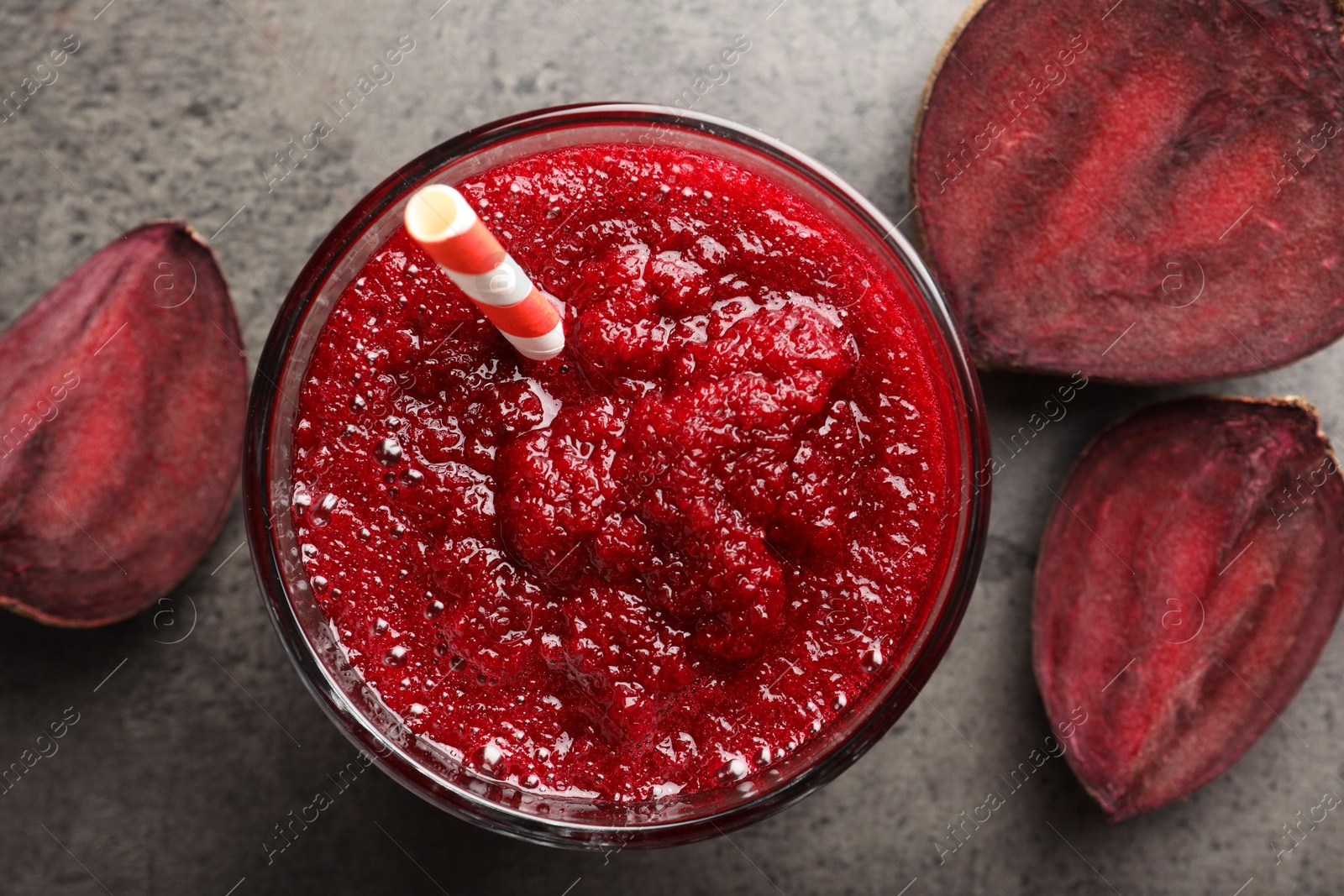 Photo of Fresh beetroot smoothie in glass and cut vegetable on grey textured table, flat lay