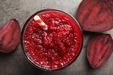 Photo of Fresh beetroot smoothie in glass and cut vegetable on grey textured table, flat lay