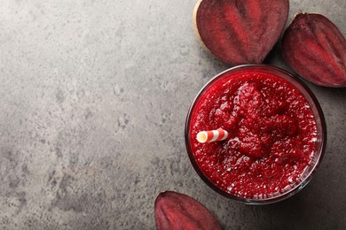 Photo of Fresh beetroot smoothie in glass and cut vegetable on grey textured table, flat lay. Space for text