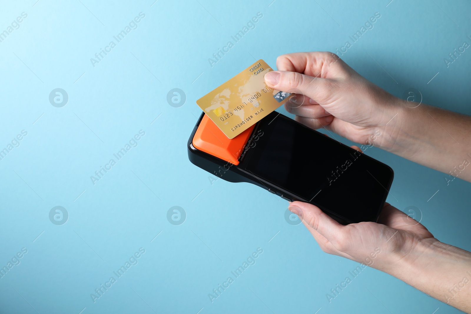 Photo of Woman with credit card using payment terminal on light blue background, closeup. Space for text