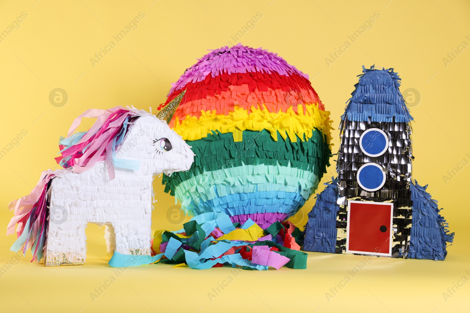 Photo of Different bright colorful pinatas on yellow background