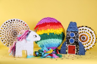 Photo of Different pinatas and party decor on yellow background