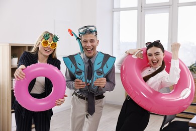 Colleagues with different beach accessories having fun in office