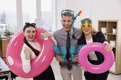 Photo of Colleagues with different beach accessories having fun in office