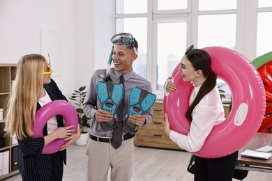 Colleagues with different beach accessories having fun in office