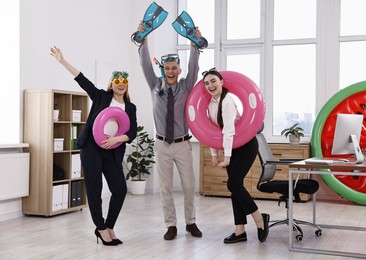 Colleagues with different beach accessories having fun in office