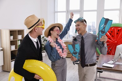 Colleagues with different beach accessories having fun in office