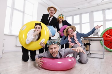 Happy coworkers with different beach accessories having fun in office, low angle view