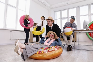 Photo of Happy coworkers with different beach accessories having fun in office, low angle view