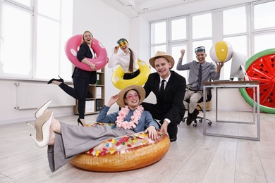 Happy coworkers with different beach accessories having fun in office, low angle view