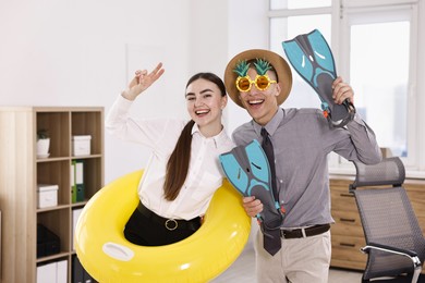 Colleagues with different beach accessories having fun in office