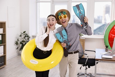 Colleagues with different beach accessories having fun in office