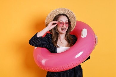 Photo of Businesswoman with inflatable ring, straw hat and sunglasses on orange background