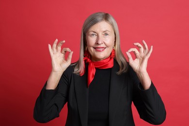 Photo of Senior woman showing okay gesture on red background