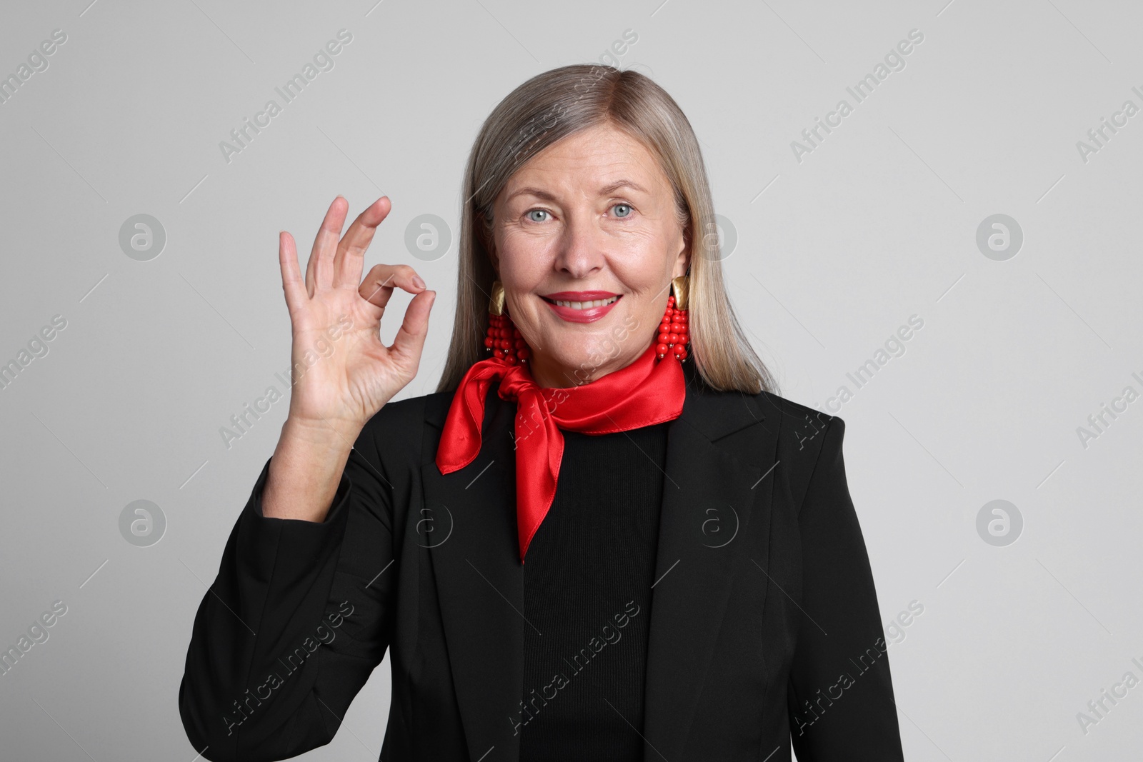 Photo of Senior woman showing okay gesture on light grey background