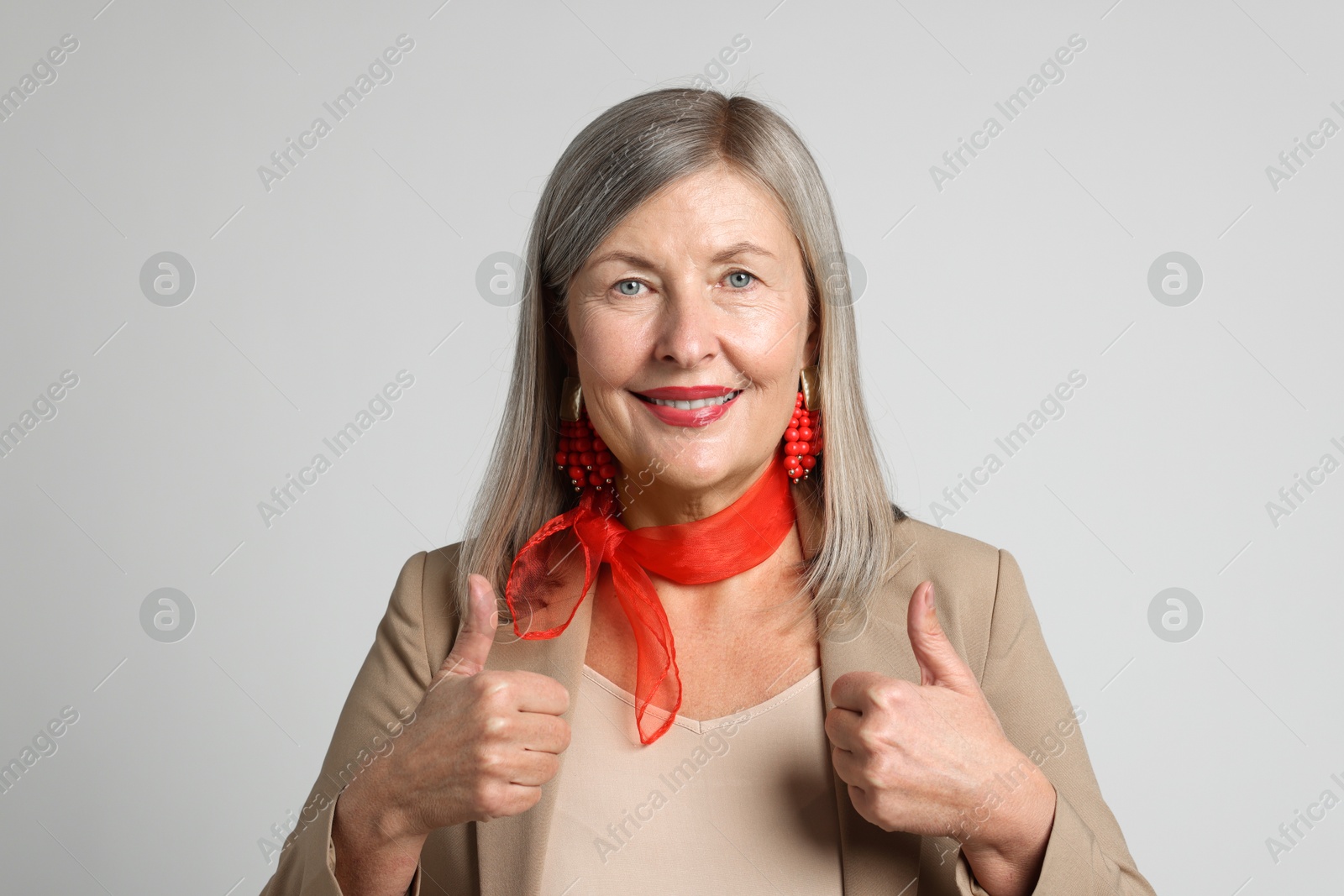 Photo of Senior woman showing thumbs up on light grey background