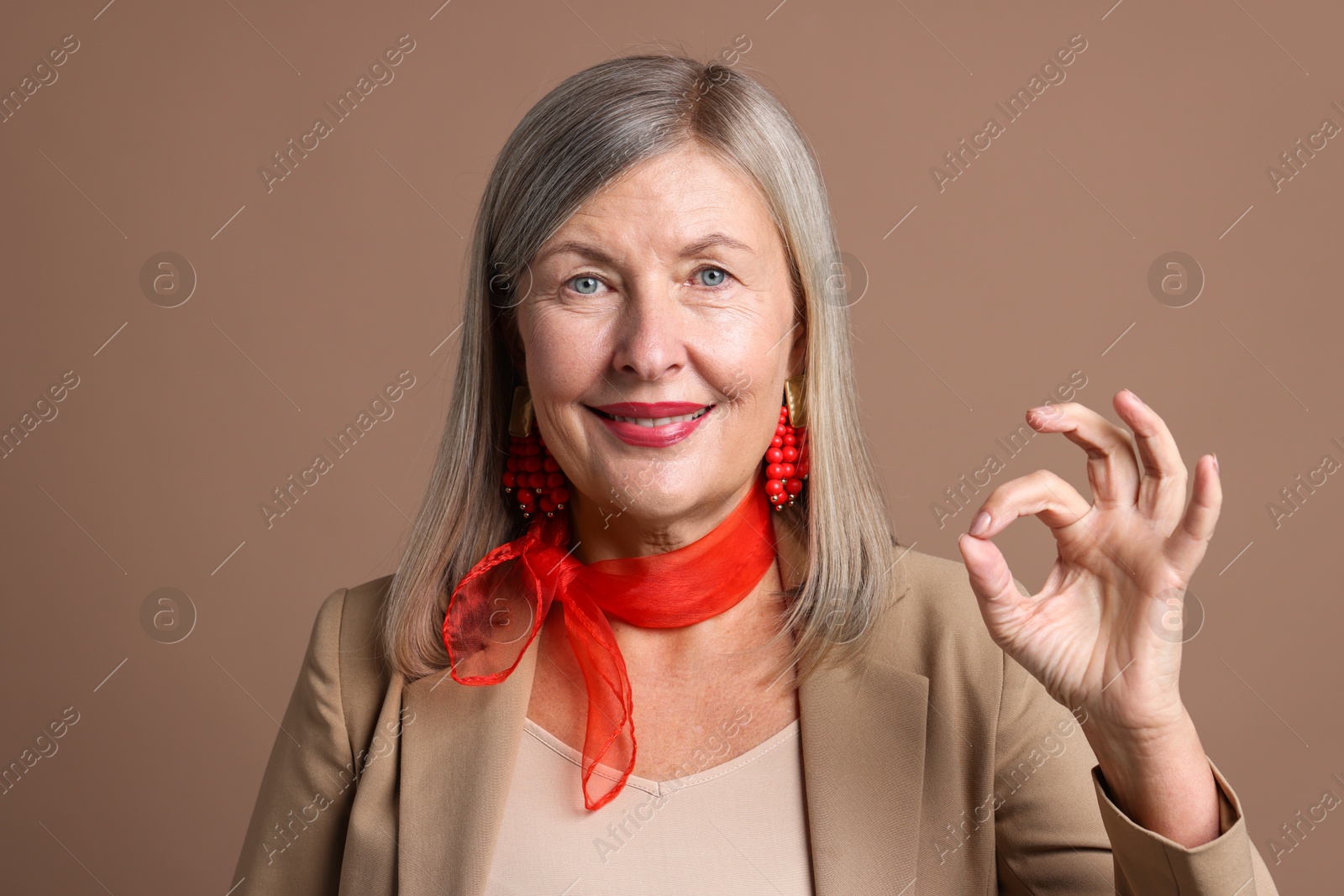 Photo of Senior woman showing okay gesture on brown background