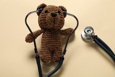 Photo of Pediatrics concept. Toy bear with stethoscope on beige background