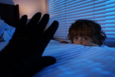 Photo of Bogeymen reaching for scared boy in bedroom at night, closeup