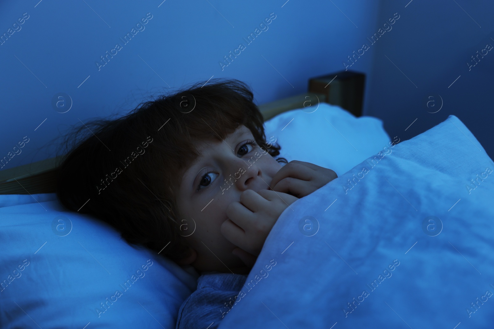 Photo of Scared boy lying in bed at night