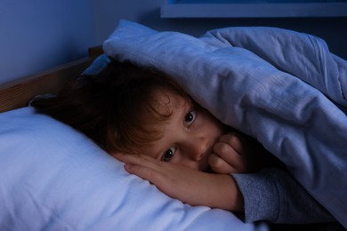 Photo of Scared boy under duvet in bed at night