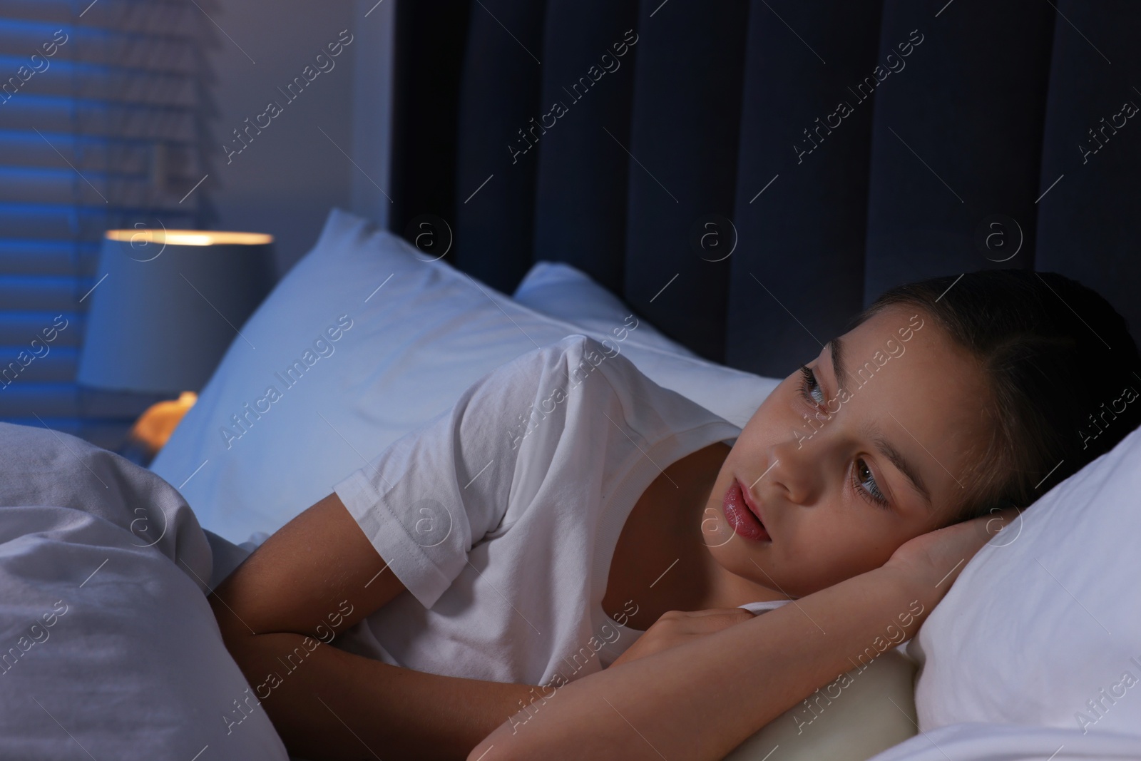 Photo of Scared girl lying in bed at night