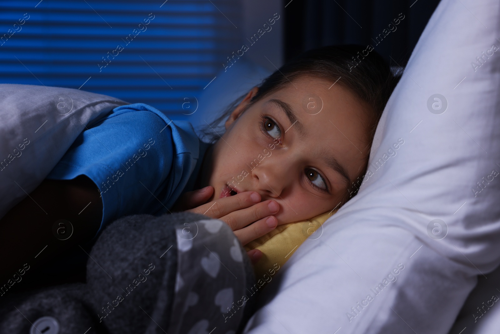 Photo of Afraid girl with toy in bed at night