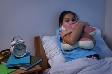 Photo of Afraid girl with pillow in bed at night