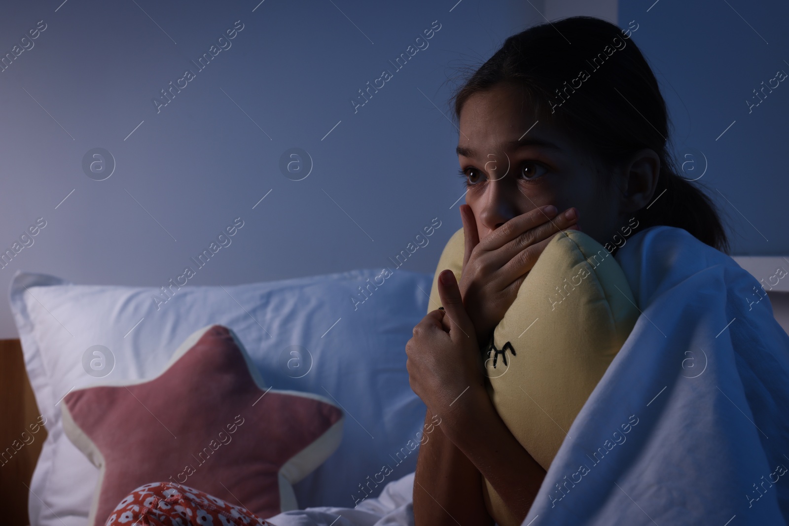 Photo of Afraid girl with pillow under duvet on bed at night. Space for text