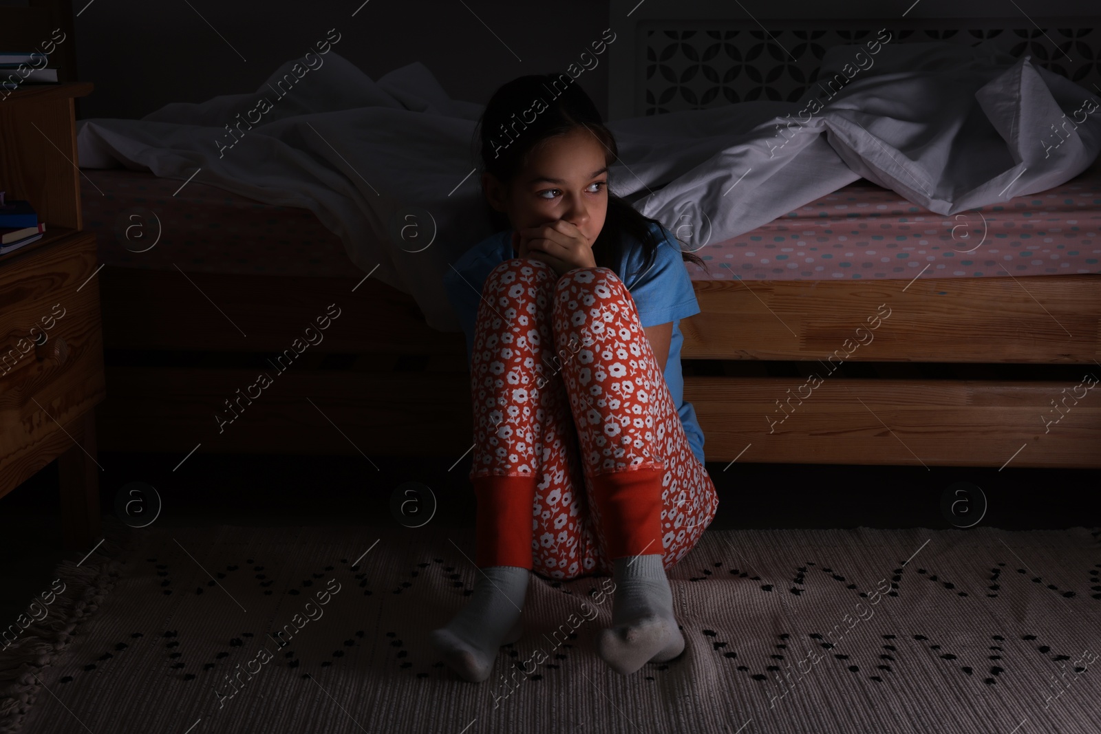 Photo of Afraid girl near bed in her room at night